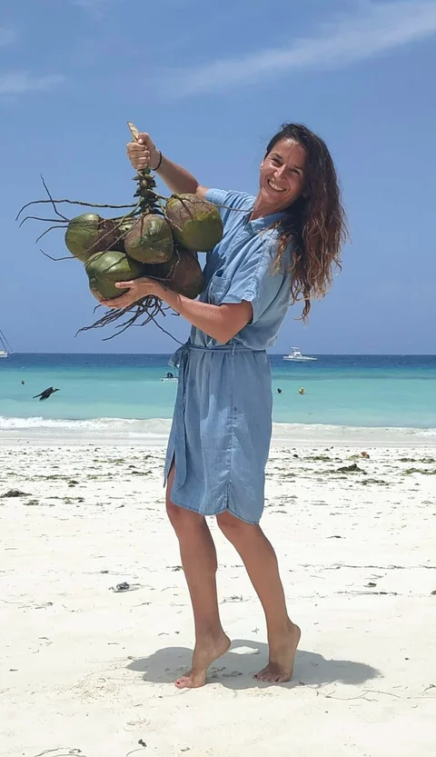 Kristina Lenard, co-founder of Green Yogi Traveler, on the beach with coconuts