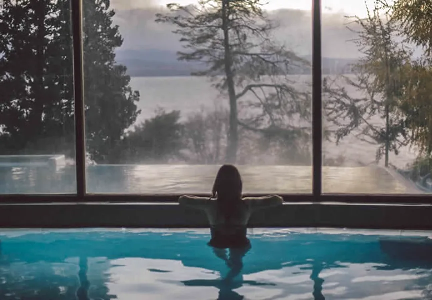 Guest relaxing in the spa pool looking out to the misty Patagonian lake, Design Suites Hotel