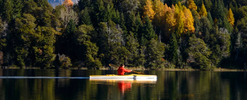 Kayaker on a calm Patagonian lake framed by autumn forest and mountains, Argentina