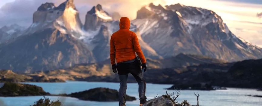 Hiker overlooking a glacial lake and Patagonian mountains at golden hour, Argentina