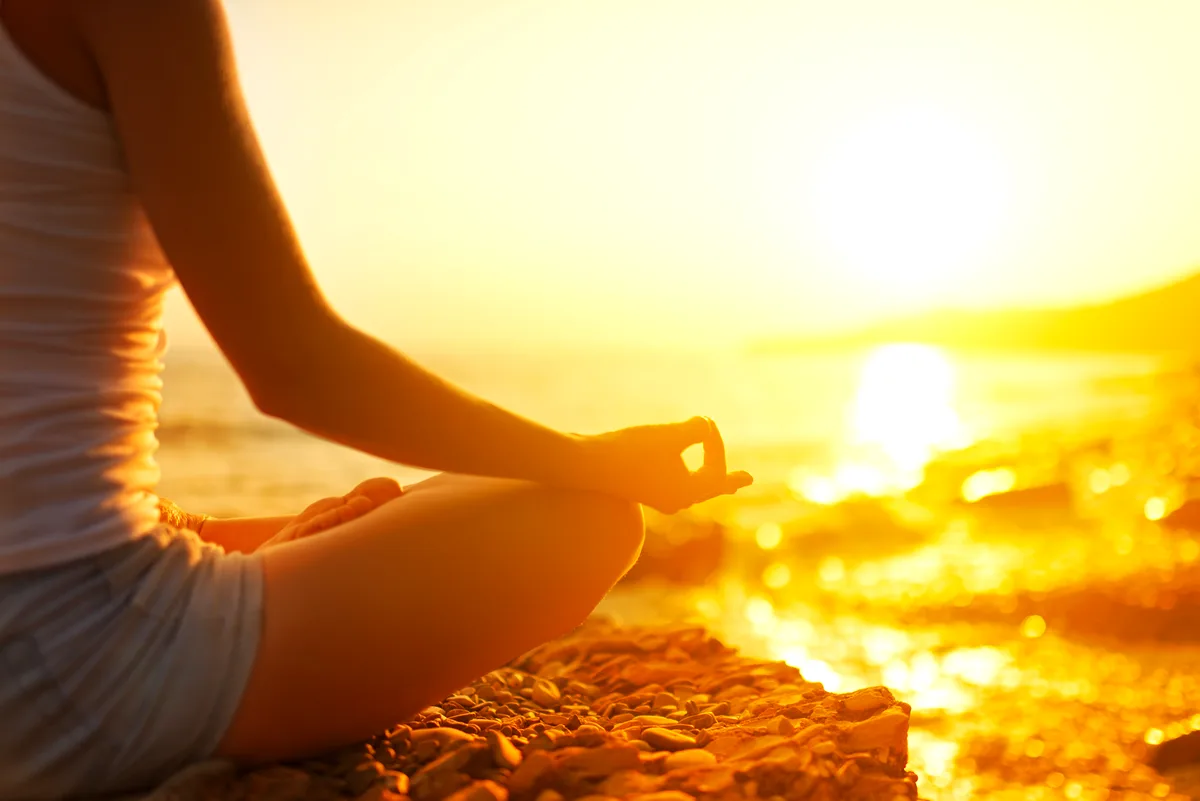 Meditating by the sea at golden sunset