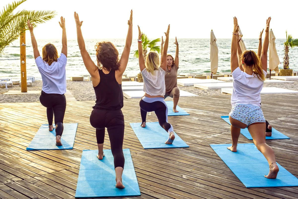 Small group yoga class by the sea at sunset