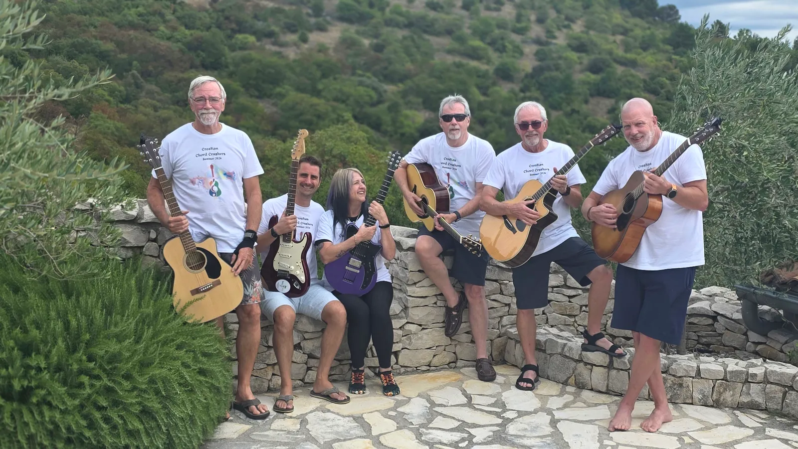 Guitar retreat guests playing guitars together on stone steps in Rabac