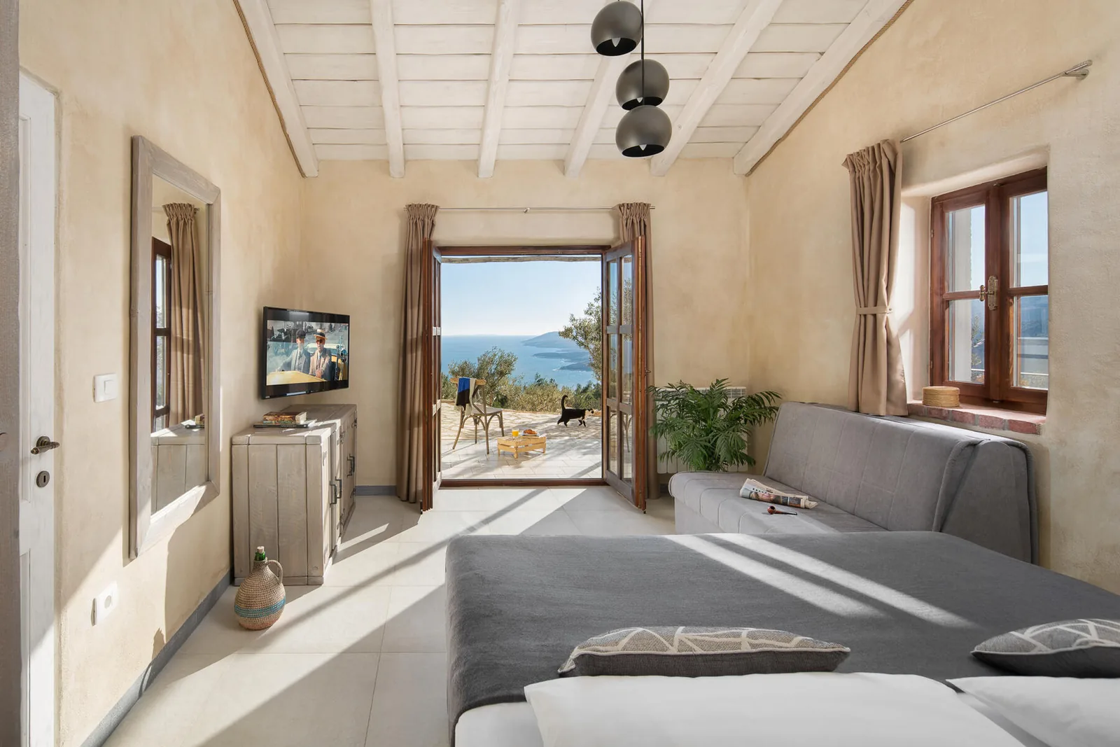 Bedroom with doors opening to a sunny terrace and the sea view at the villa in Rabac