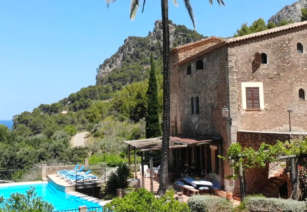 Stone finca with palm and pool below the Tramuntana mountains — yoga retreat Mallorca, Spain