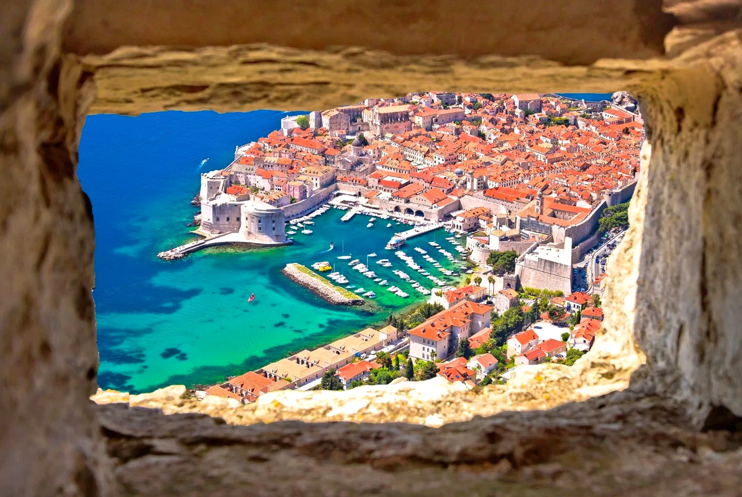 View of Dubrovnik old town and harbour framed through a stone window, Croatia