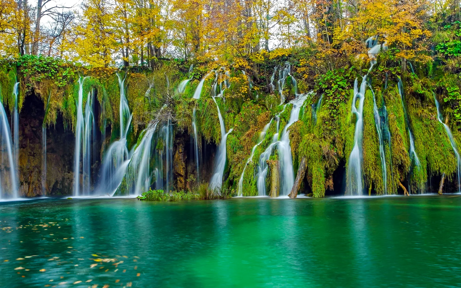 Autumn waterfalls cascading into a turquoise lake at Plitvice Lakes National Park, Croatia