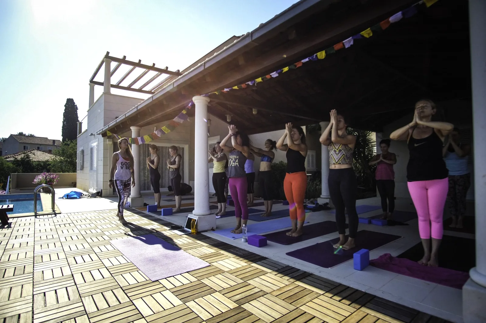 Group yoga practice under the covered terrace with prayer flags at Villa Gumonca, Brač Island