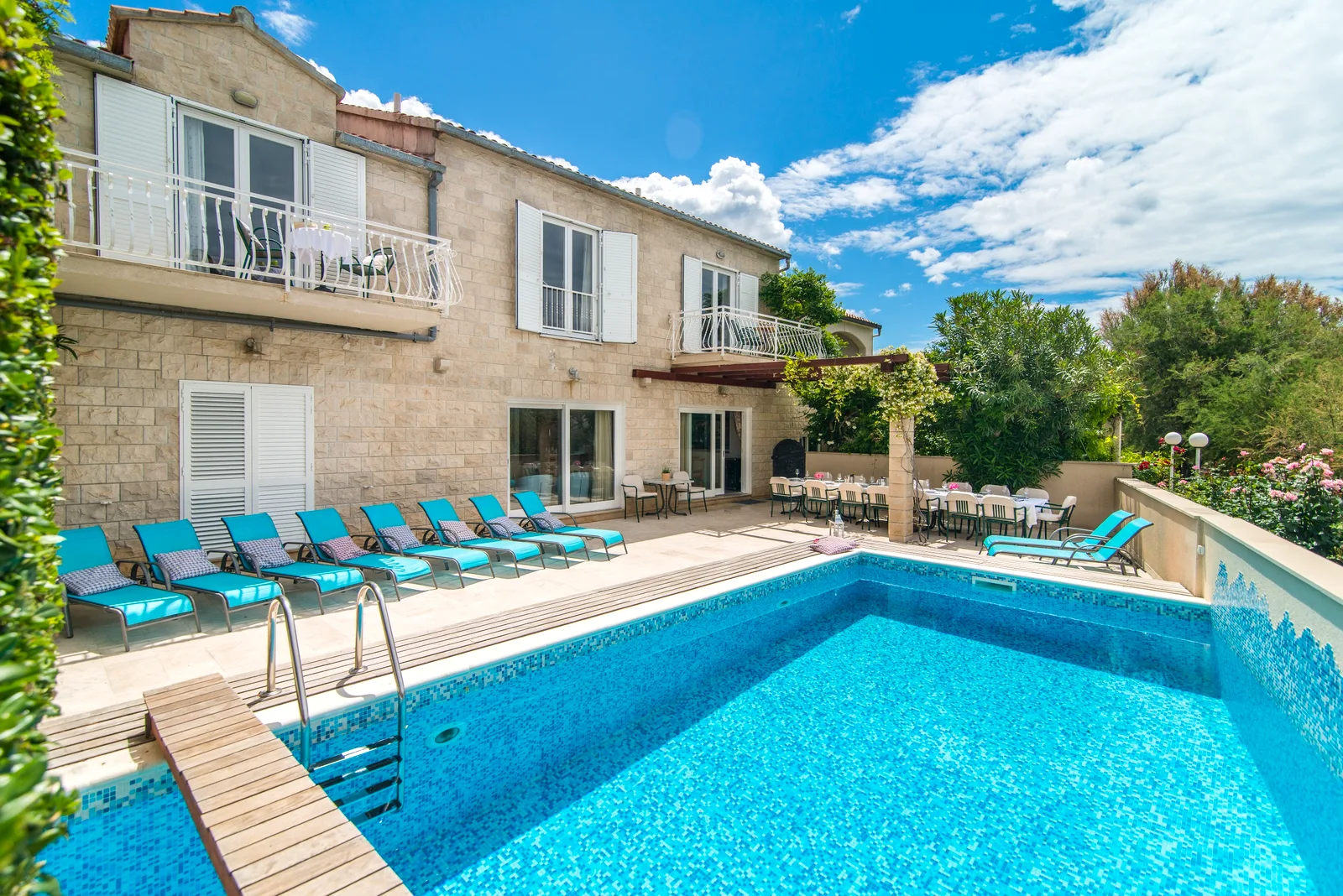 Pool terrace with sun loungers below the stone facade of Villa Mirca, retreat venue on Brač Island, Croatia