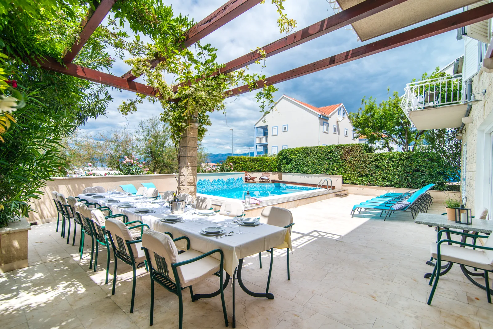 Long group dining table set under the pergola beside the pool at Villa Mirca, Brač Island, Croatia