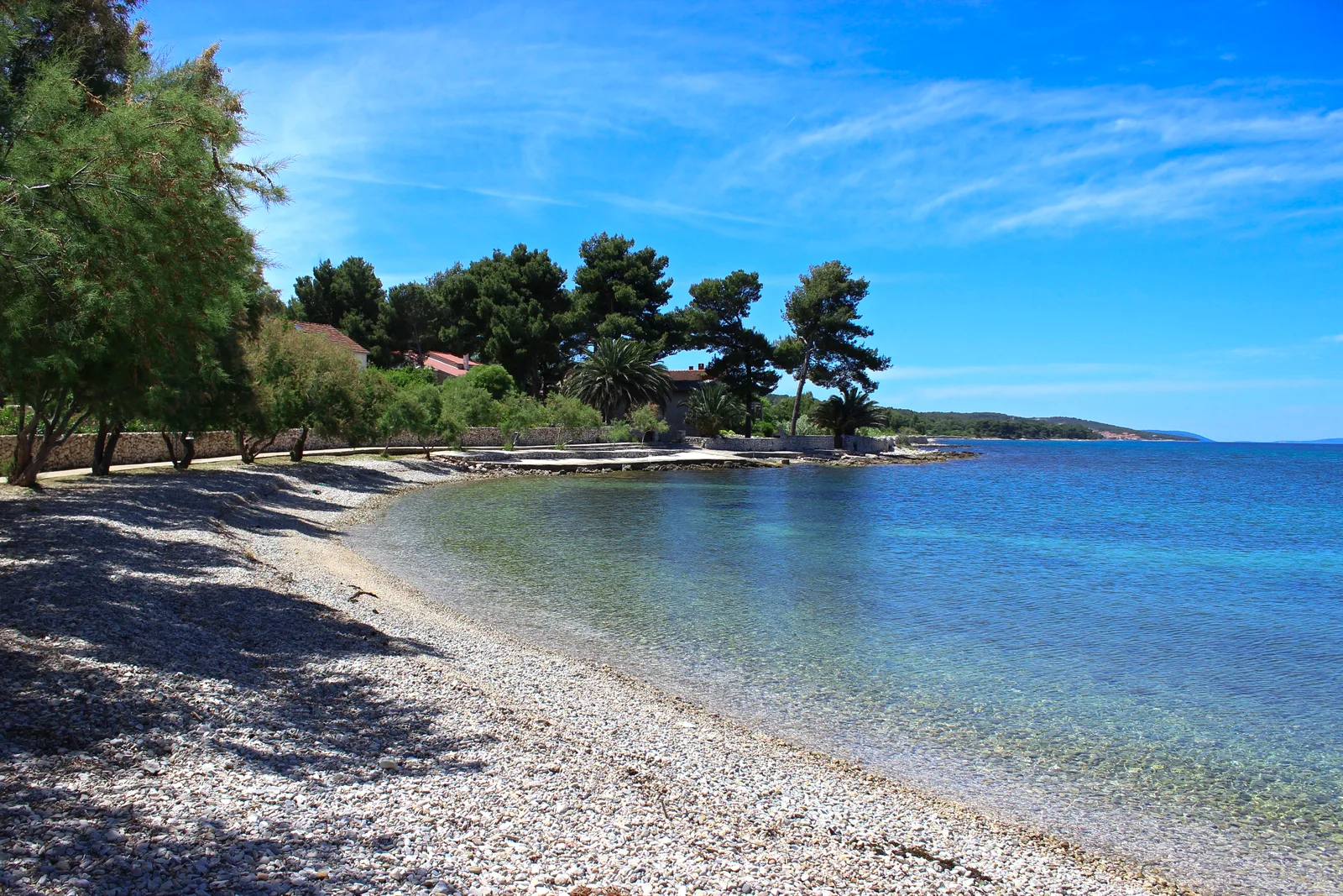 The private pebble beach and clear shallow water below Villa Mirca, Brač Island, Croatia