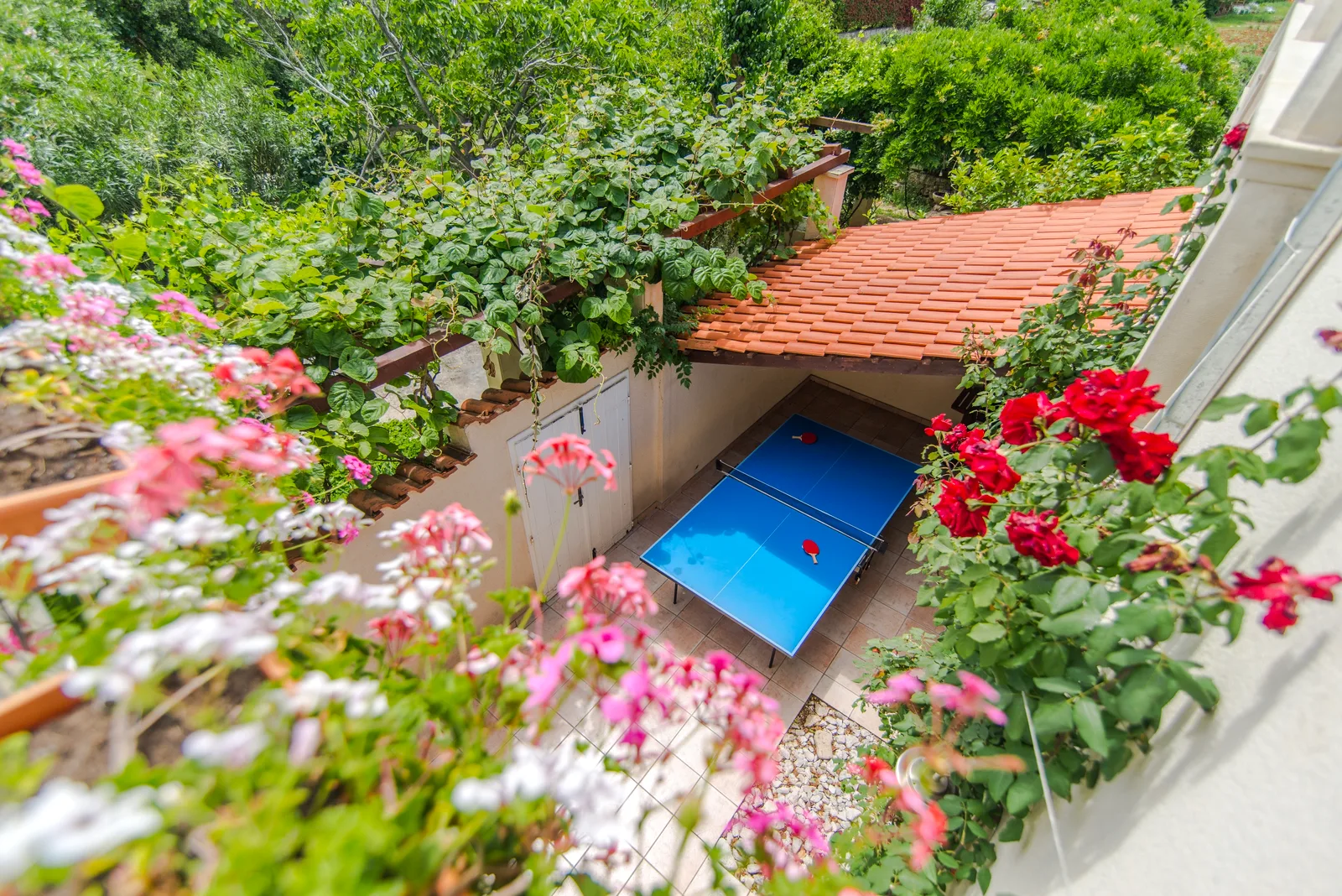 Table tennis on a covered terrace surrounded by flowers at Villa Mirca, Brač Island, Croatia