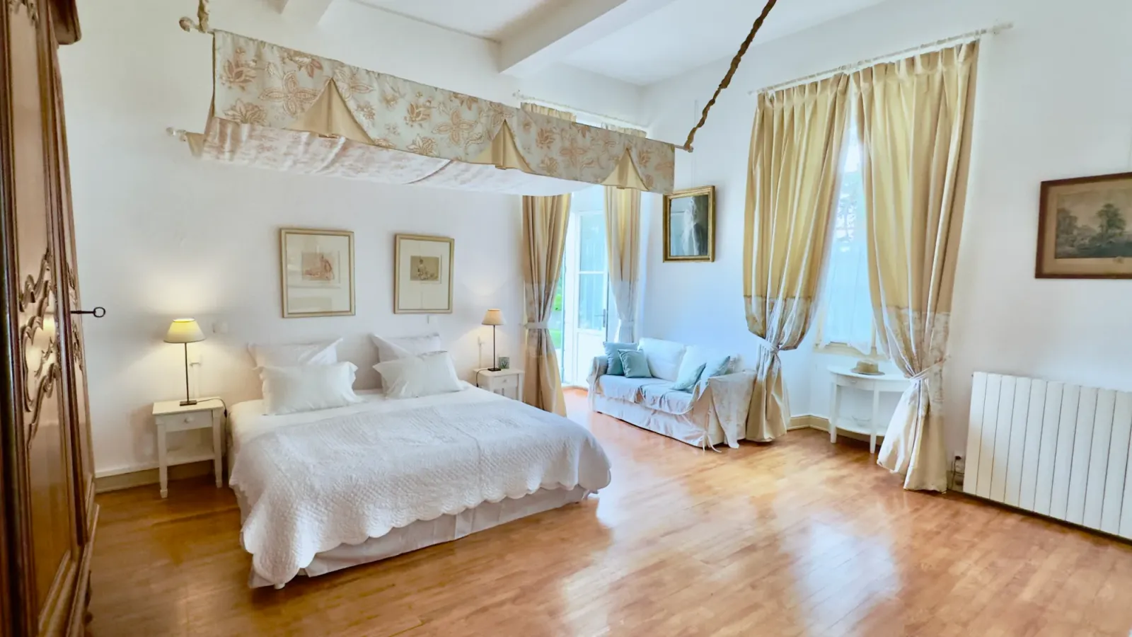 Château bedroom with canopy bed and sitting area at Château de Lassalle, France