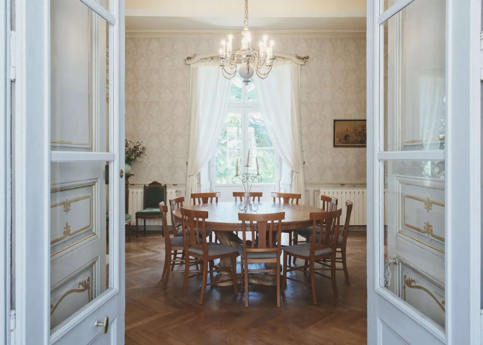 Formal dining room with round table and chandelier at Château de Lassalle, France