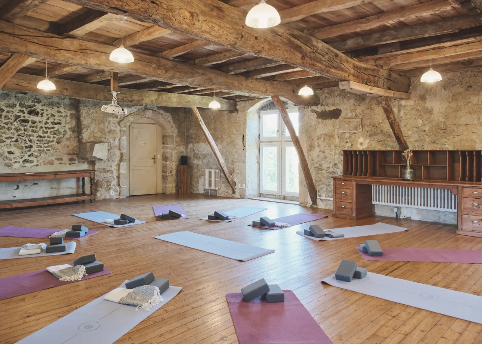 Yoga studio with timber beams, wooden floor and mats at Château de Lassalle, France
