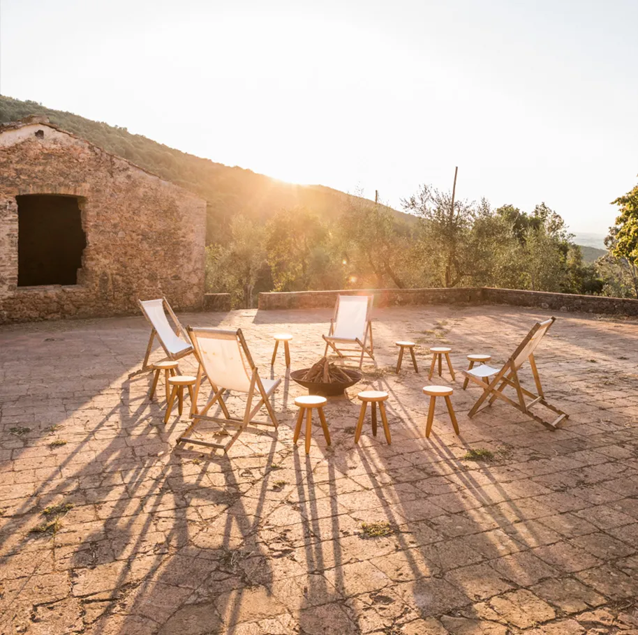 Stone patio terrace with chairs in the evening sun at Ebbio Tuscany, Italy