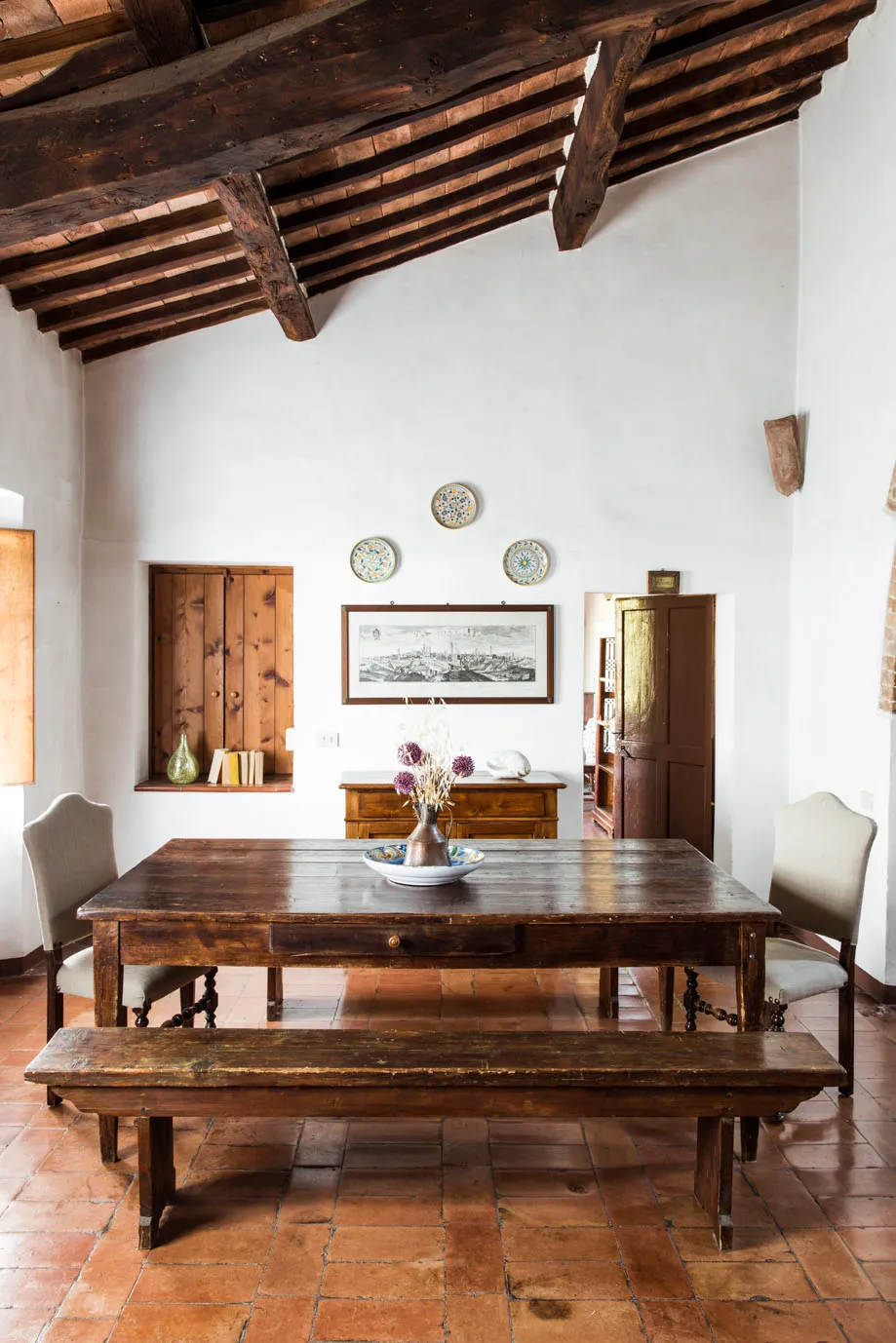 Dining room with long wooden table and chandelier at Ebbio Tuscany, Italy