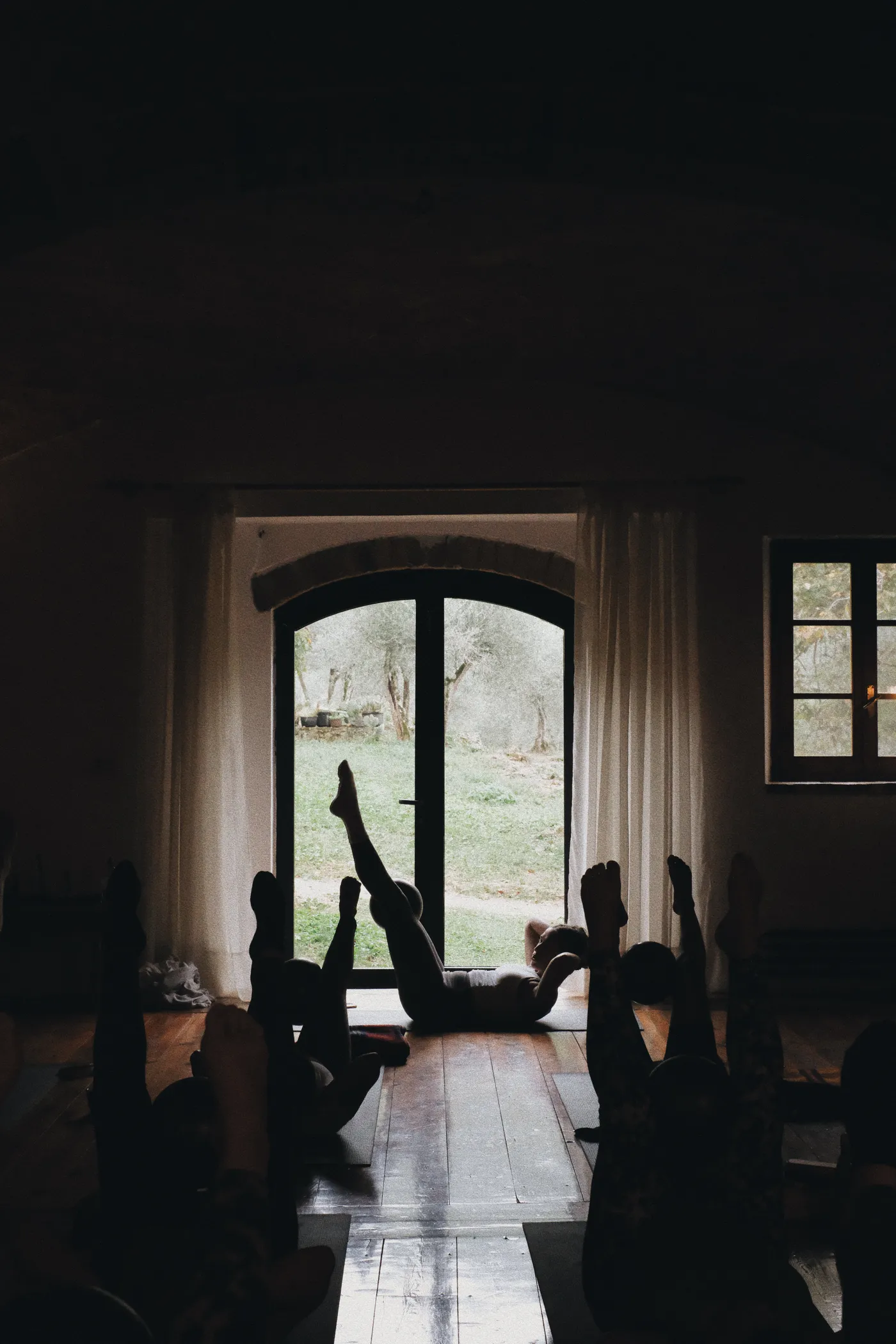 Group practicing yoga by an arched window at Ebbio Tuscany, Italy