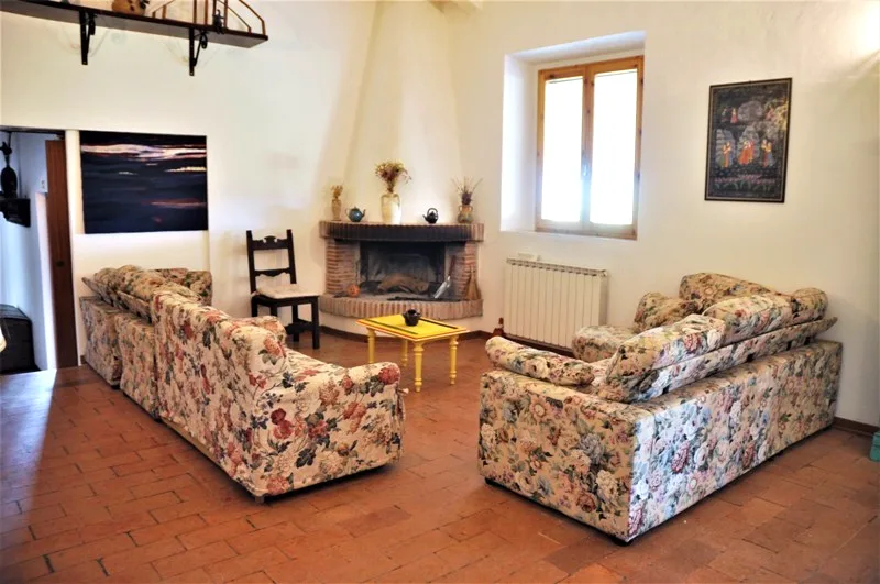 Living room with floral sofas and a brick fireplace at Il Risveglio, Tuscany