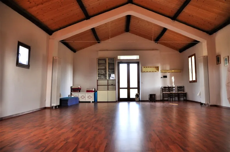 Empty yoga hall with vaulted wood-beamed ceiling at Il Risveglio, Tuscany