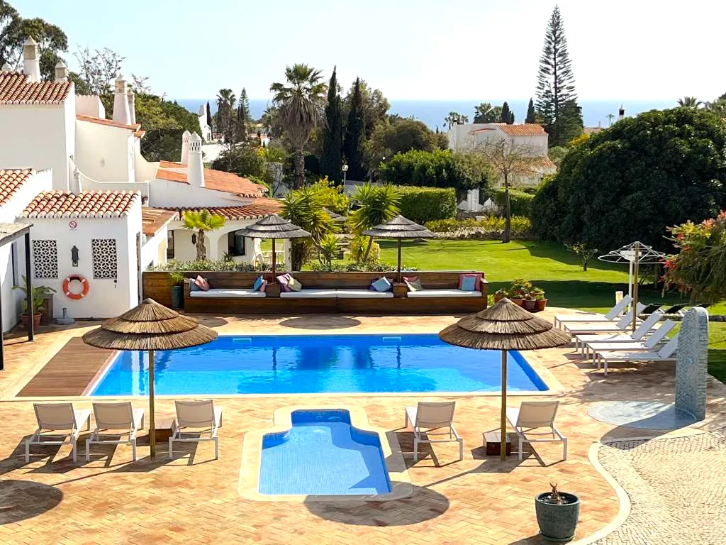 Poolside straw umbrellas and garden at Villa Vale a Pena, Carvoeiro, Algarve