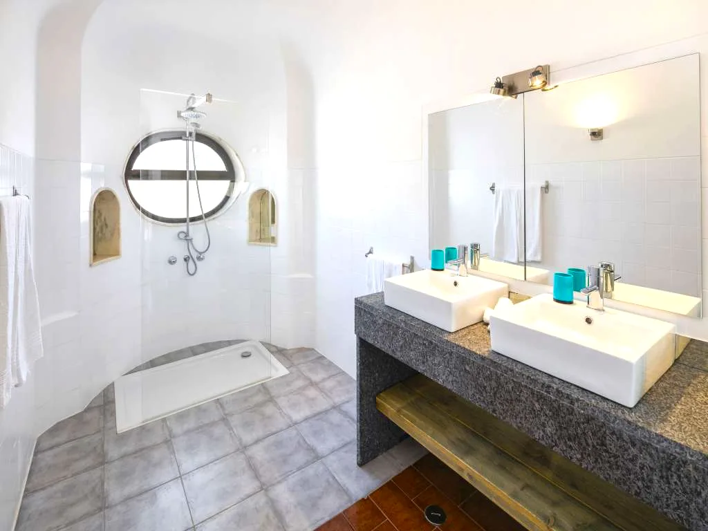 En-suite bathroom with a double sink and oval window at Villa Vale a Pena, Algarve, Portugal