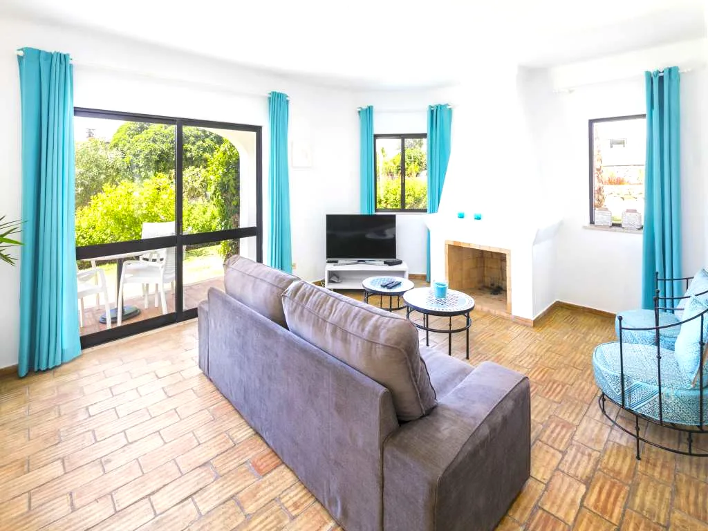 Living room with fireplace and teal curtains at Villa Vale a Pena, Algarve, Portugal