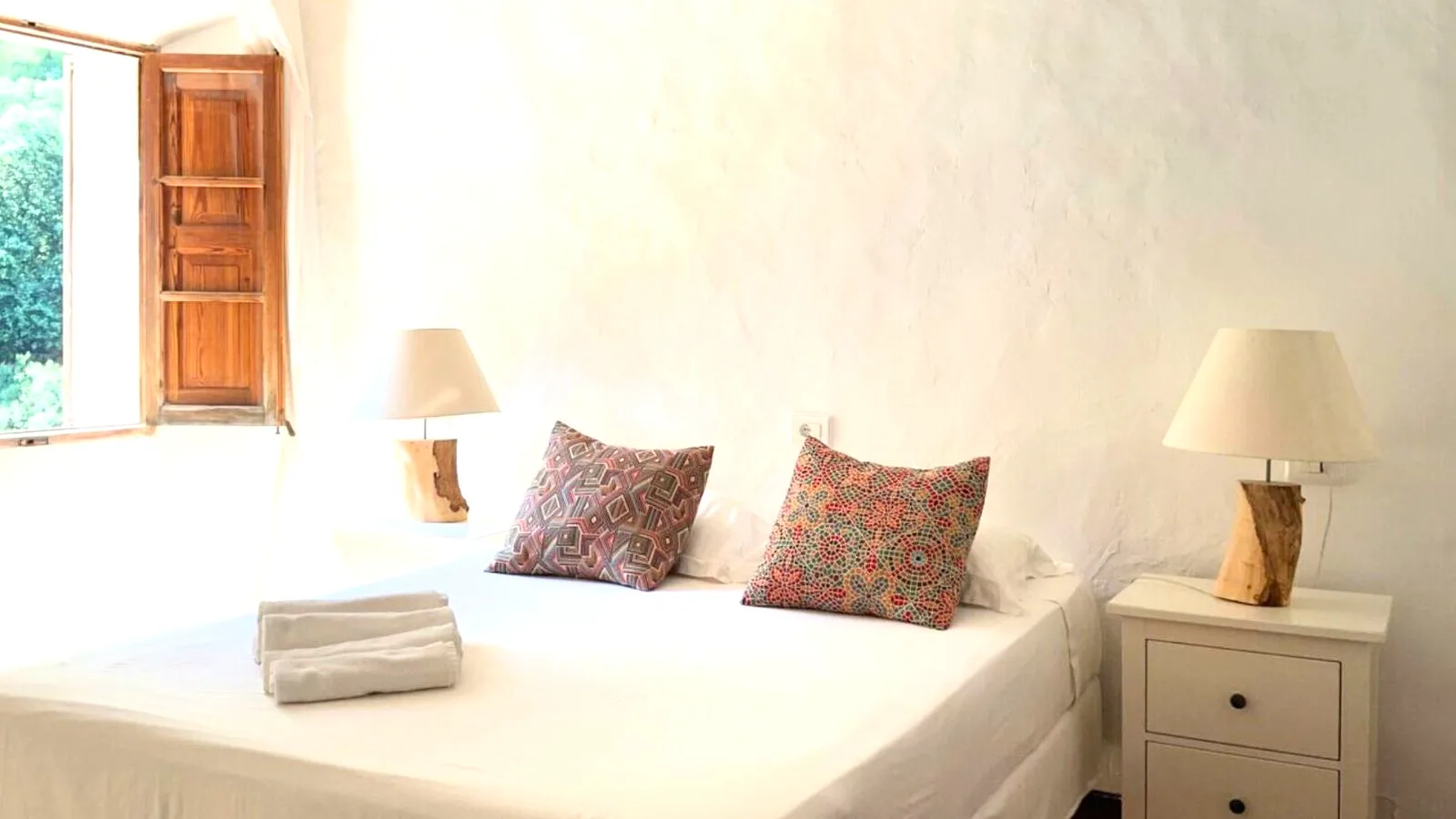 Bedroom with a wooden shuttered window open to the garden at Finca Higo, Mallorca