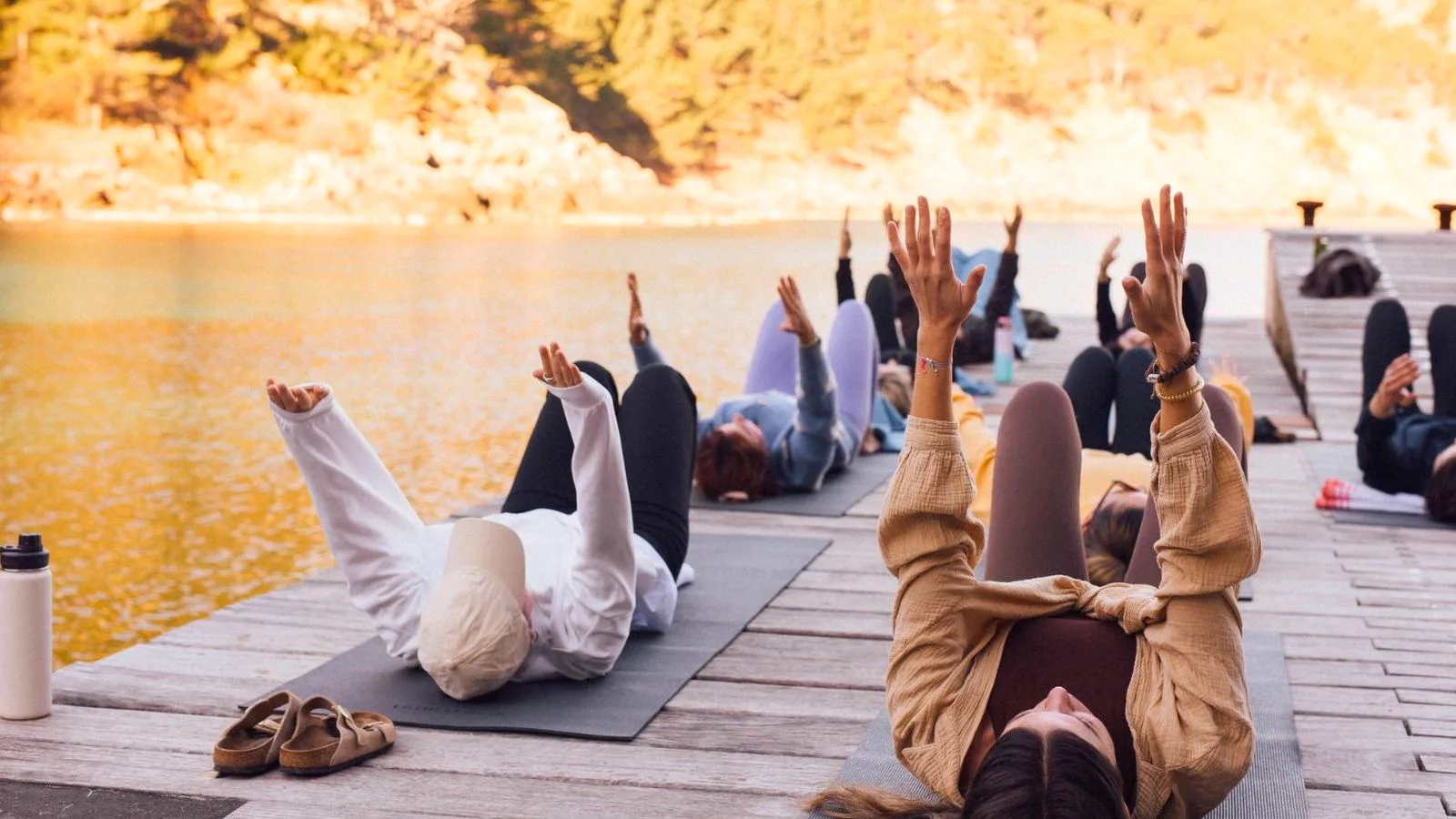 Yoga group practicing at golden hour on a dock above the cove at Finca Higo, Mallorca