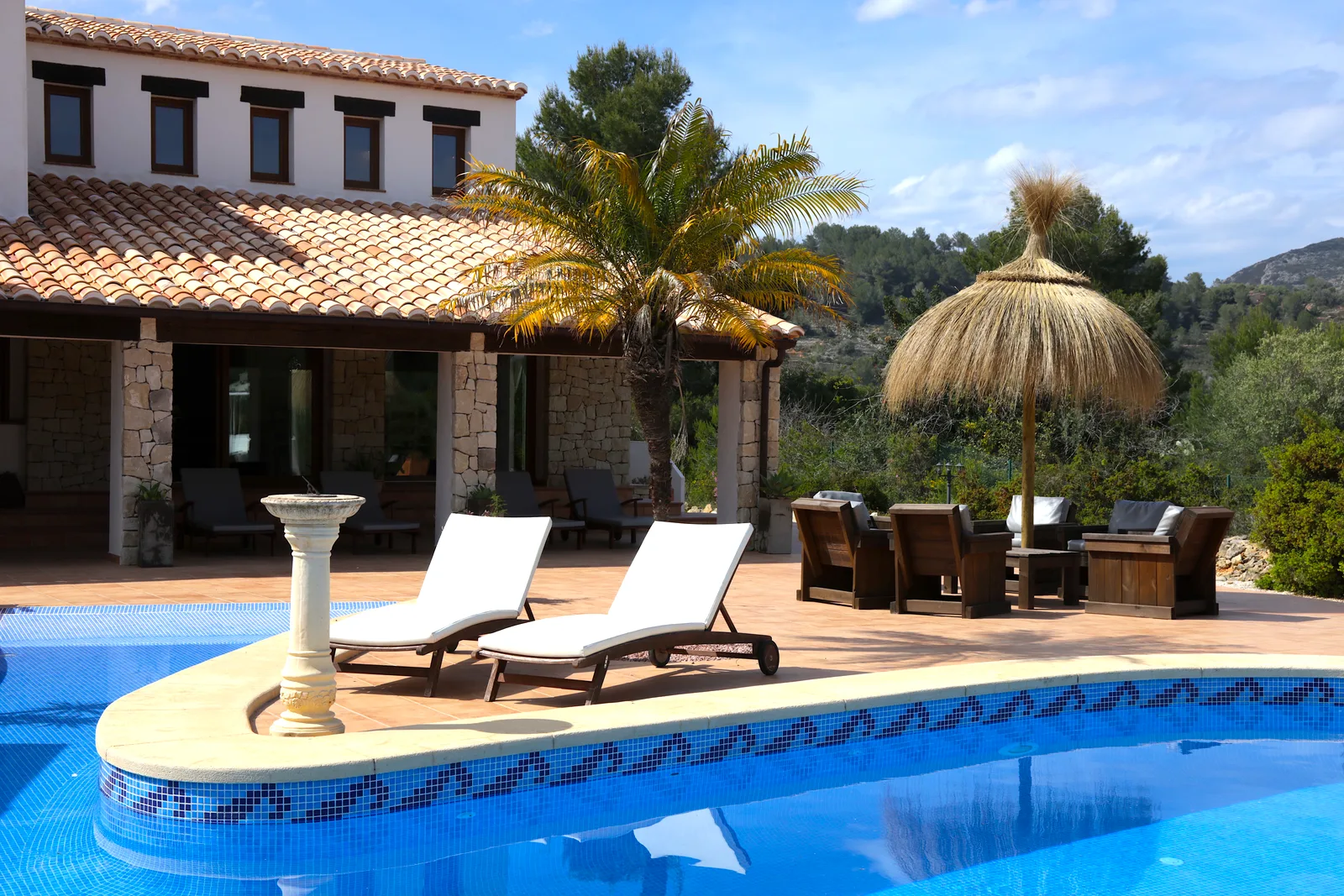 Pool terrace and villa facade with palm tree at Oodles, Costa Blanca, Spain