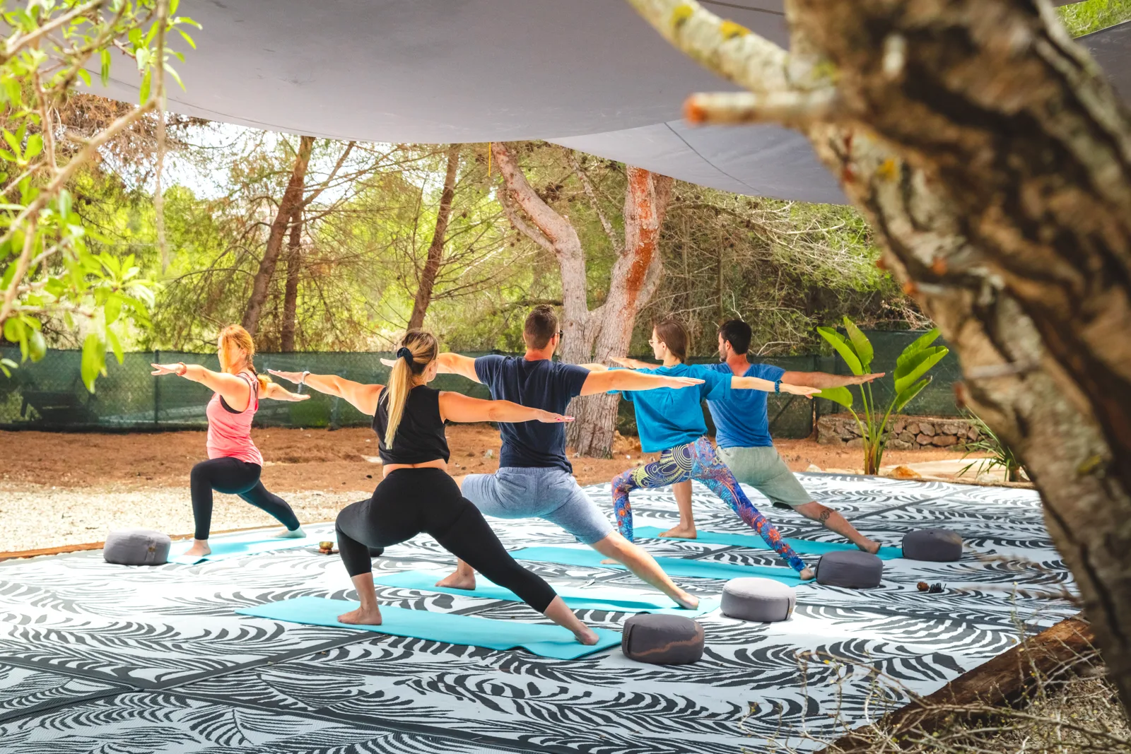 Yoga group in warrior pose on the outdoor deck at the Oodles villa, Spain