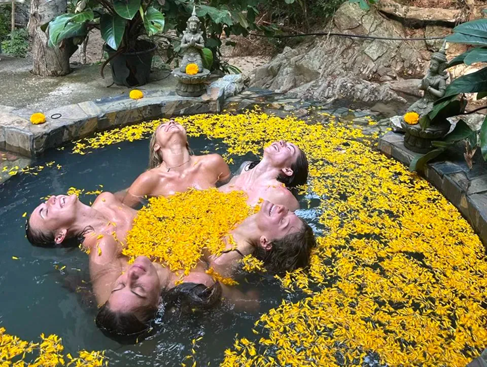 Group in a golden flower-petal bath ritual at Shivari, Koh Phangan