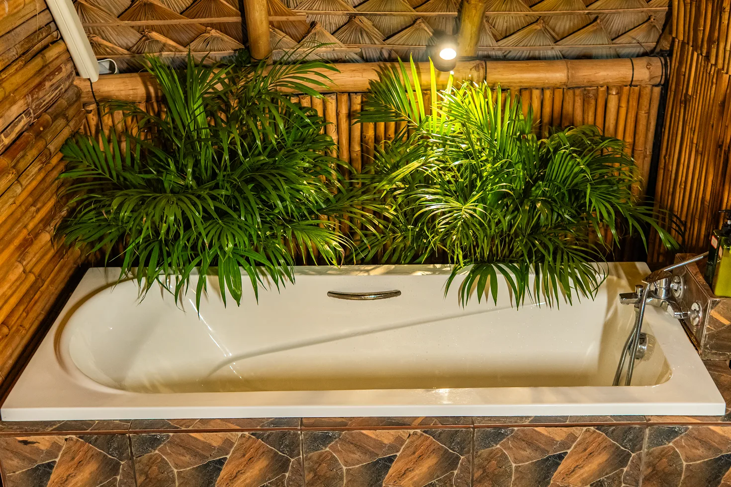 Bathtub surrounded by jungle plants in a Shivari bungalow bathroom
