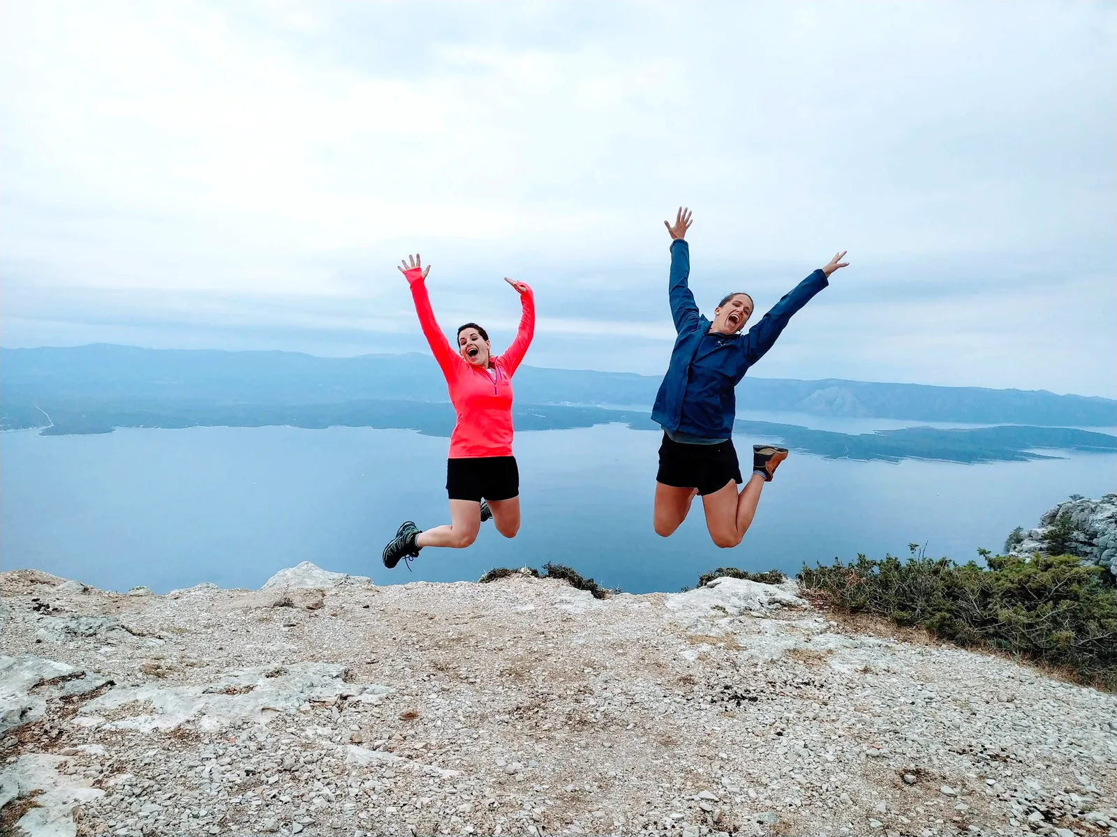 Two retreat guests jumping with joy on Vidova Gora above the Adriatic, Brač Island, Croatia