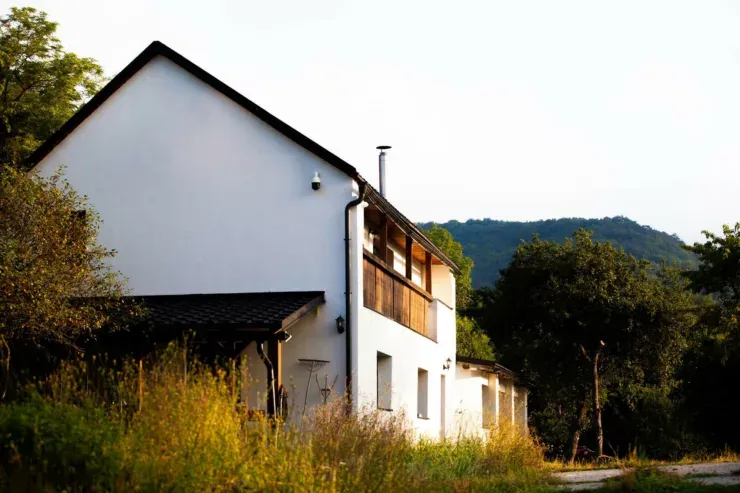 White farmhouse at Terra Belá in evening light with wooded hills behind