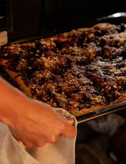 Hands lifting a freshly baked fruit cake from the oven