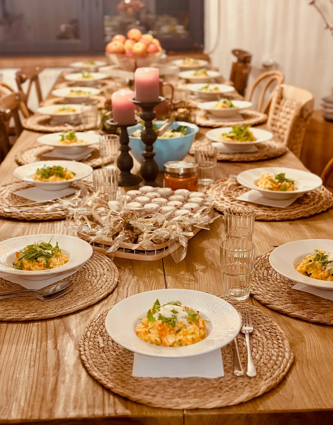 Long wooden dinner table set with bowls, candles and placemats at Terra Belá